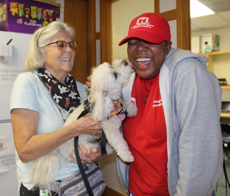 Two ladies, one in red USACE shirt with therapy dog.
