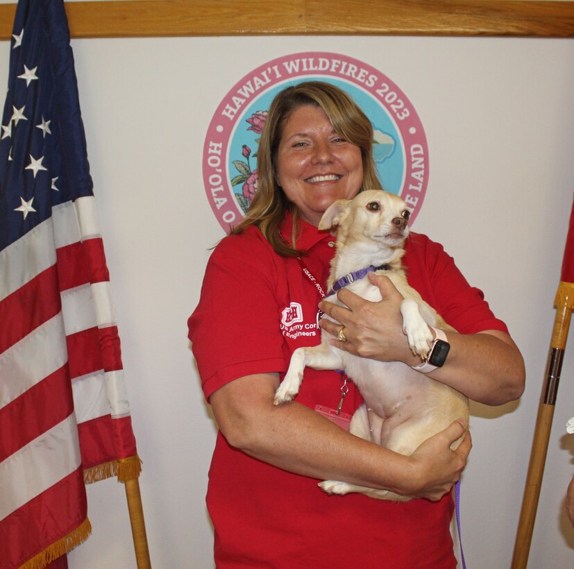 Woman in red USACE shirt holding therapy dog.