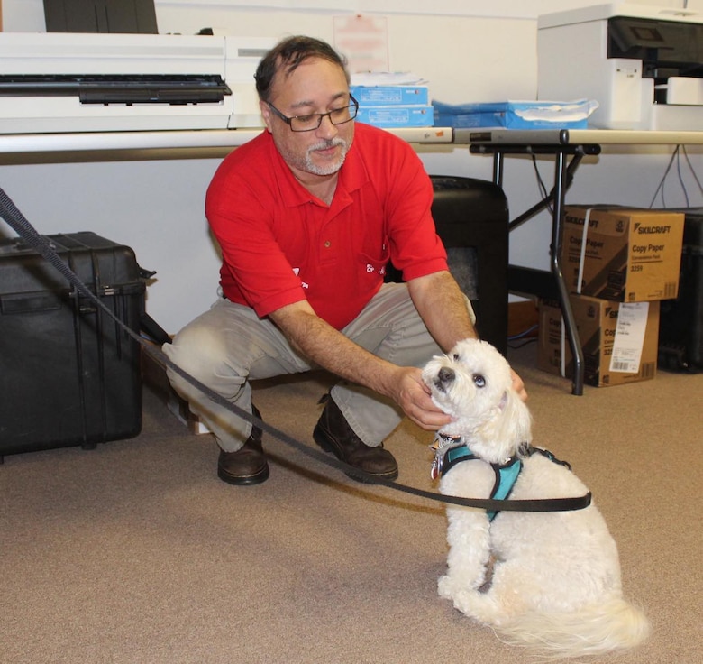 Man in red USACE shirt petting therapy dog