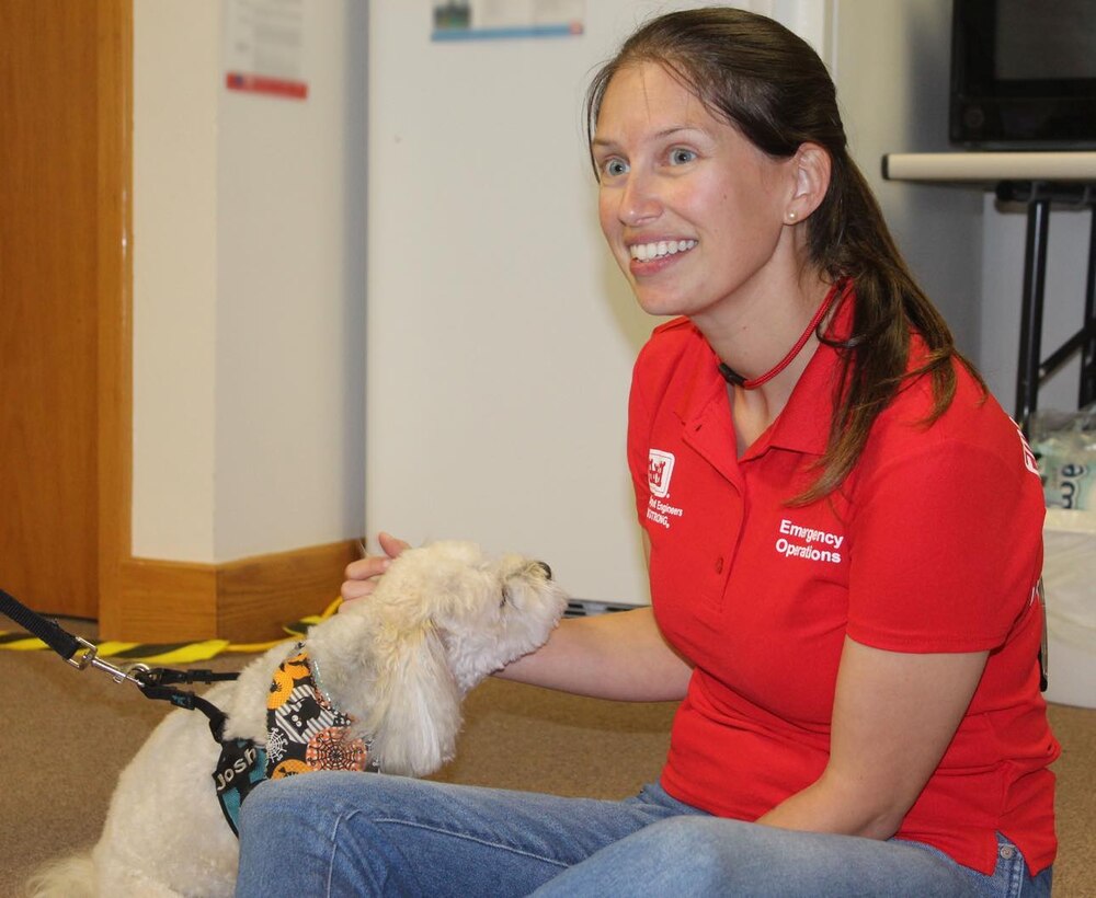 Woman in USACE red shirt petting therapy dog
