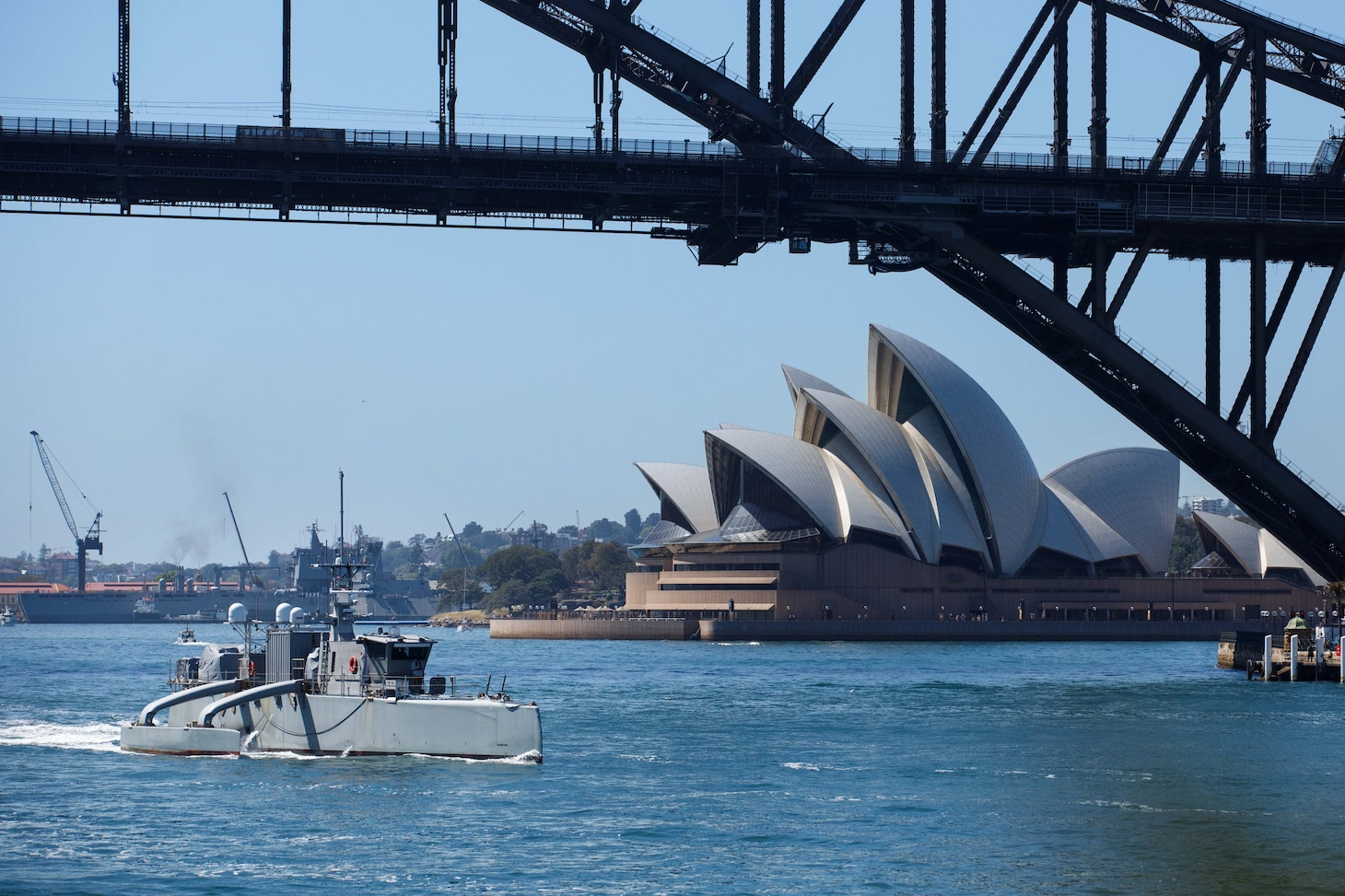 The unmanned surface vessel Sea Hunter transits underneath the Sydney Harbor bridge as part of a scheduled port visit during Integrated Battle Problem (IBP) 23.2, Oct 24, 2023. IBP 23.2 is a Pacific Fleet exercise to test, develop and evaluate the integration of unmanned platforms into fleet operations to create warfighting advantages. (U.S. Navy photo by Ensign Pierson Hawkins)