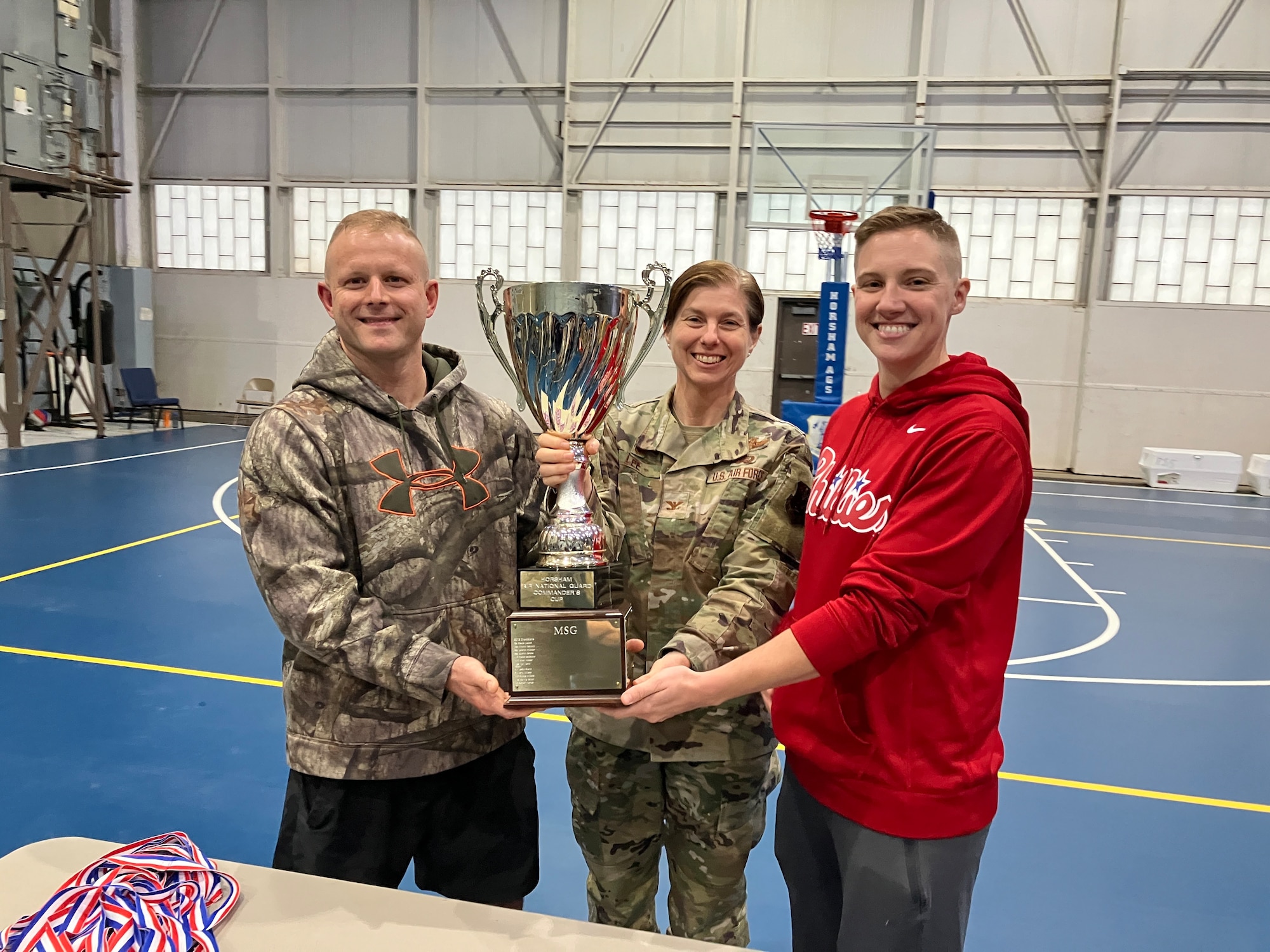 people pose holding a trophy and ribbons.