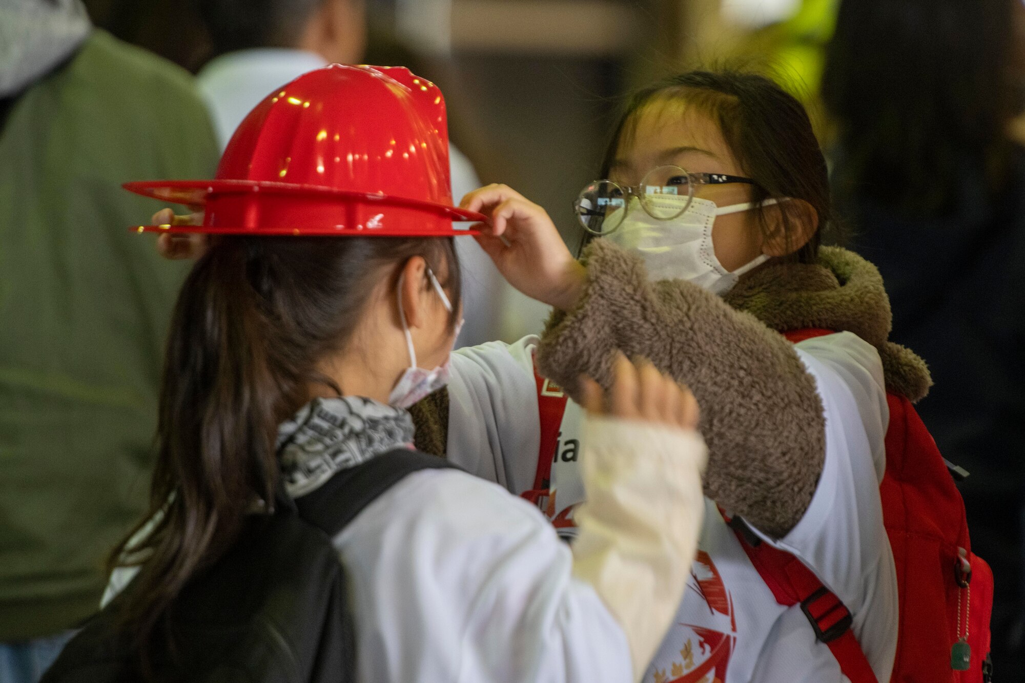 A participant places a plastic firefighter helmet on another participant during the 2023 Misawa Special Olympics at Misawa Air Base, Japan.