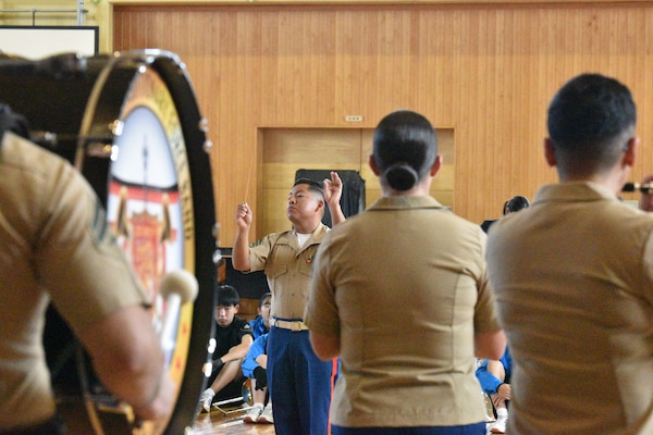 III MEF band members watch drill team students perform.