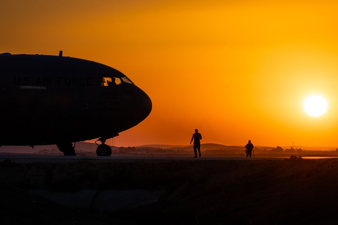 Airmen guard a C-17 Globemaster III at dusk.