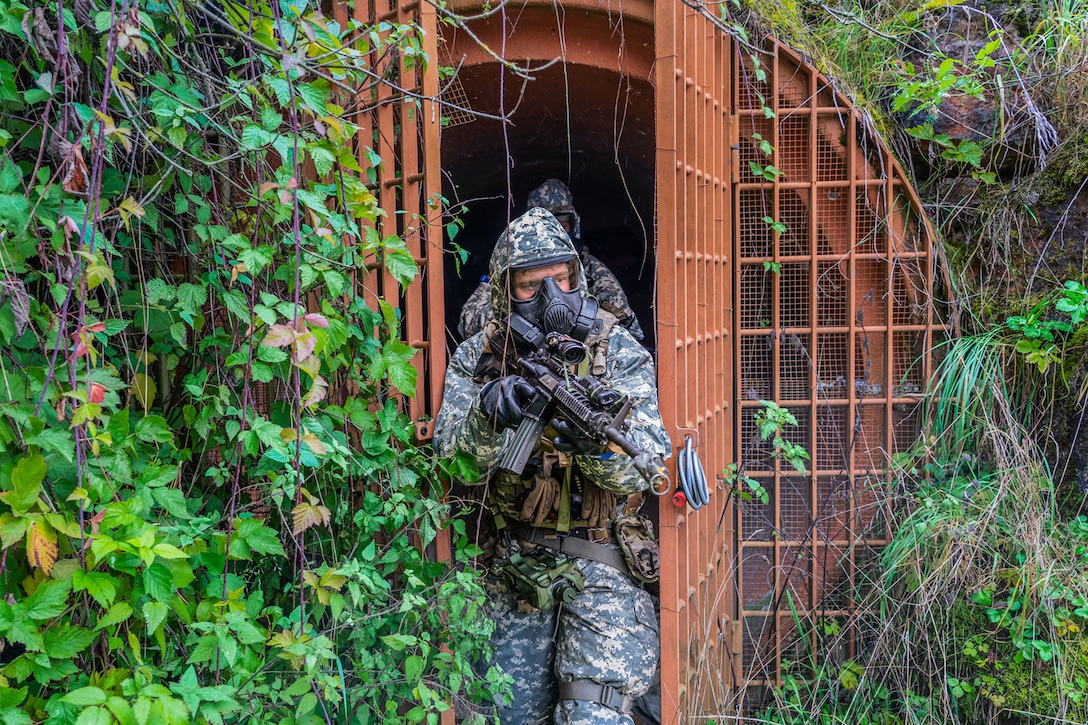 Soldiers wearing tactical gear and holding weapons exit an underground tunnel complex.