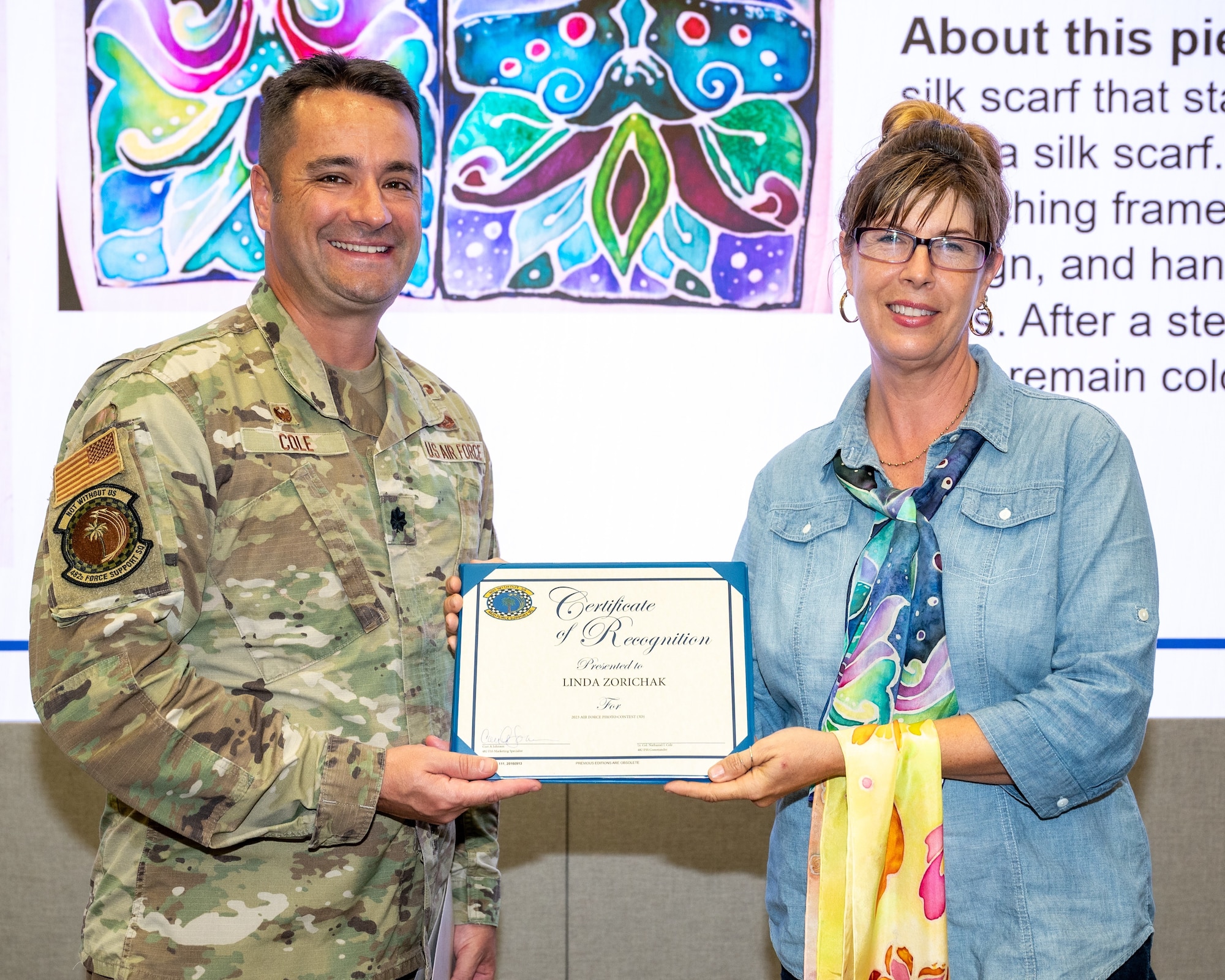 Lt. Col. Nathaniel Cole, 482d Force Support Squadron Commander, presents Ms. Linda Zorichak, 93rd Fighter Squadron unit program coordinator, with a Certificate of Recognition for taking first place in the 2023 Air Force Art Contest at Homestead Air Reserve Base, Florida, Oct. 13, 2023. (U.S. Air Force photo by Tech. Sgt. Lionel Castellano)