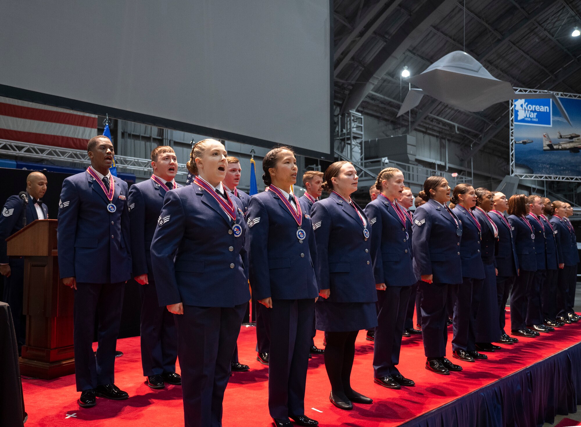 A group of Airman stand in formation on stage.
