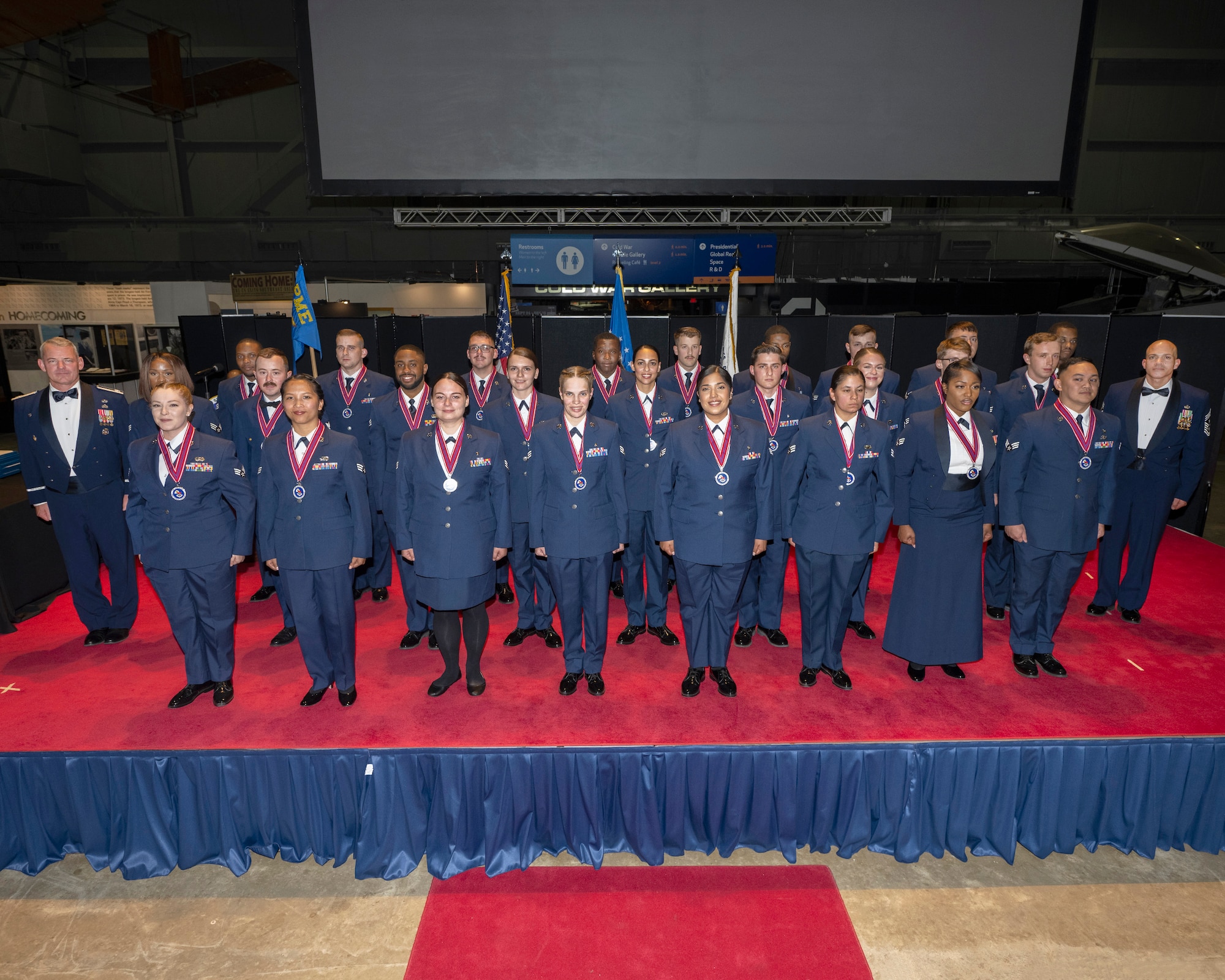 A group of Airmen stand on a stage.