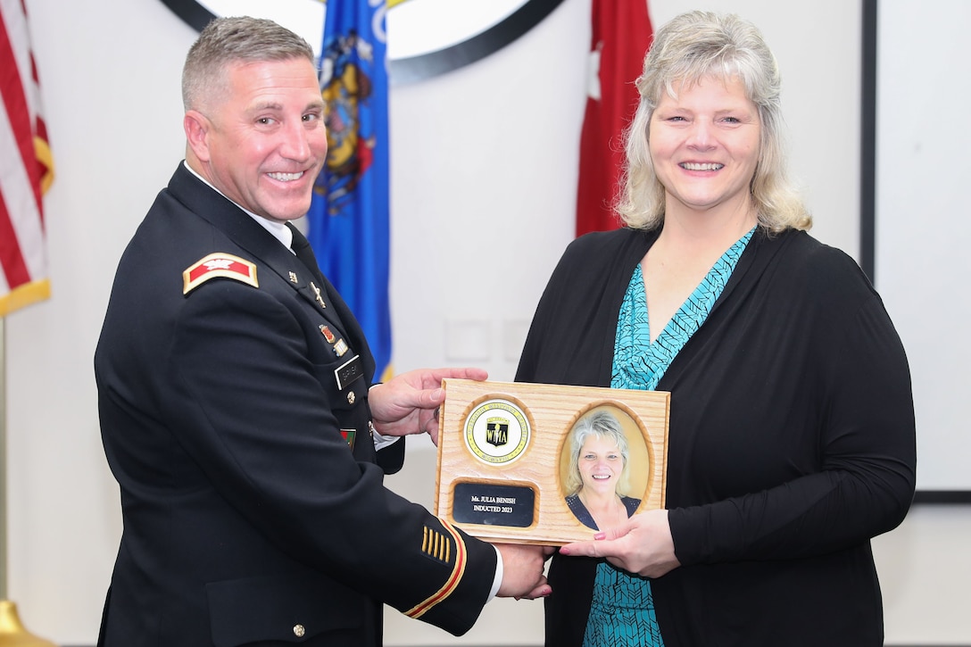 Col. Paul Gapinski, outgoing commander of the Wisconsin Army National Guard’s 426th Regiment, presents Julia Benish with a plaque signifying his induction into the 426th Regional Training Institute (RTI) Hall of Fame during an induction ceremony Oct. 14 at Fort McCoy, Wis.