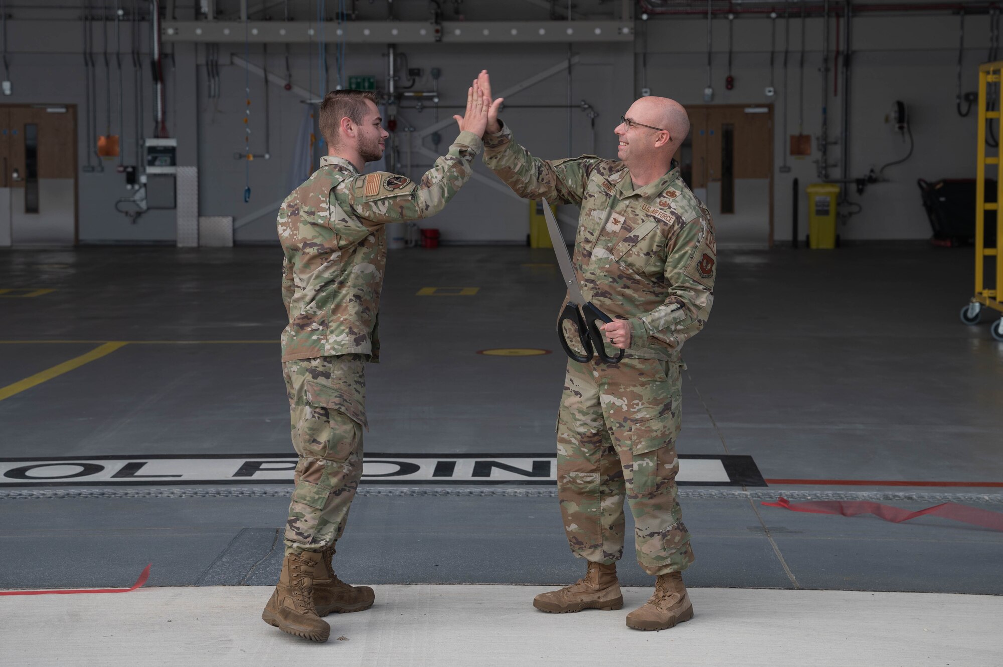 commander high fives an airmen after cutting the ribon