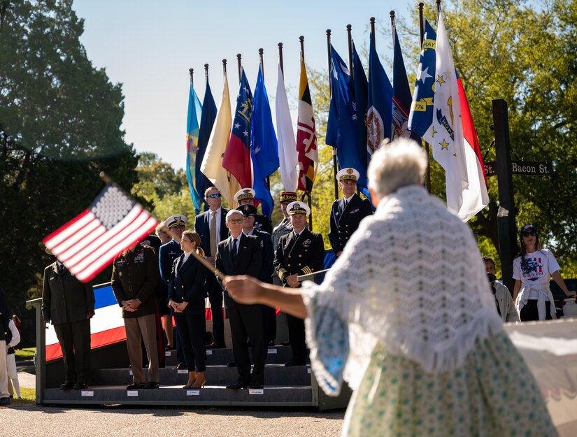 A senior woman waves a flag by the reviewing stand