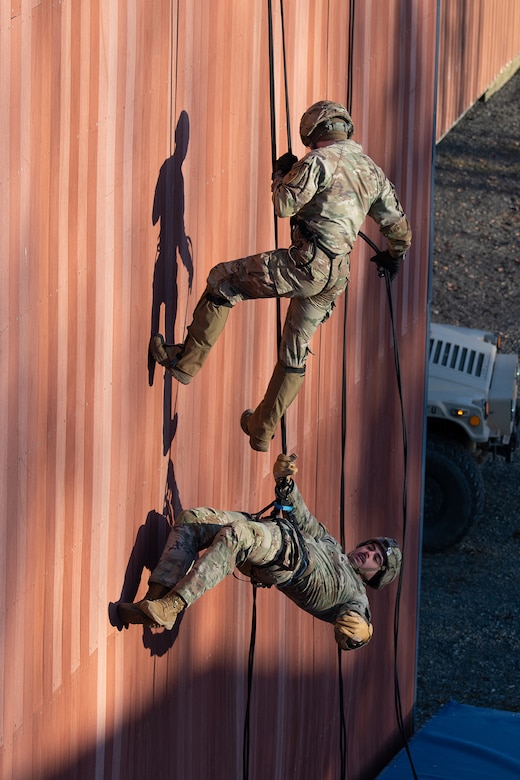 Soldiers rappel down a wall during training.
