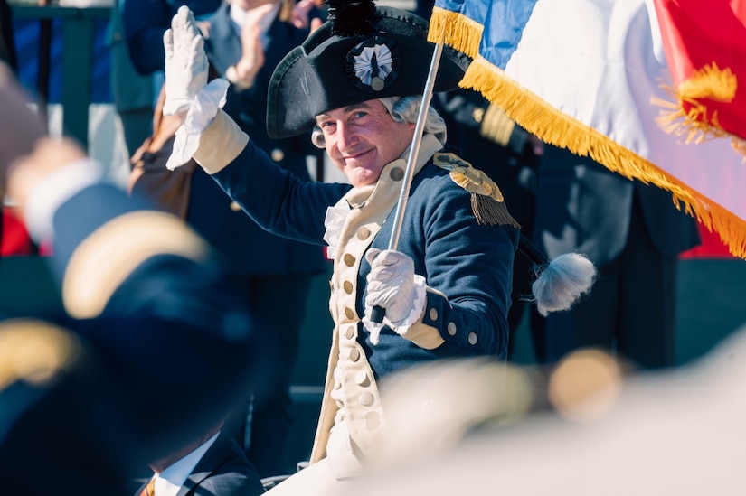A reenactor dressed as Lt. Gen. Comte de Rochambeau waves to the crowd during the Yorktown Day Parade, Oct. 19, 2023, Yorktown, Virginia. Lt. Gen. Comte de Rochambeau, being a veteran of 14 blockades in Europe, provided valuable expertise at the Siege of Yorktown. (U.S. Air Force photo by Airman 1st Class Ian Sullens)