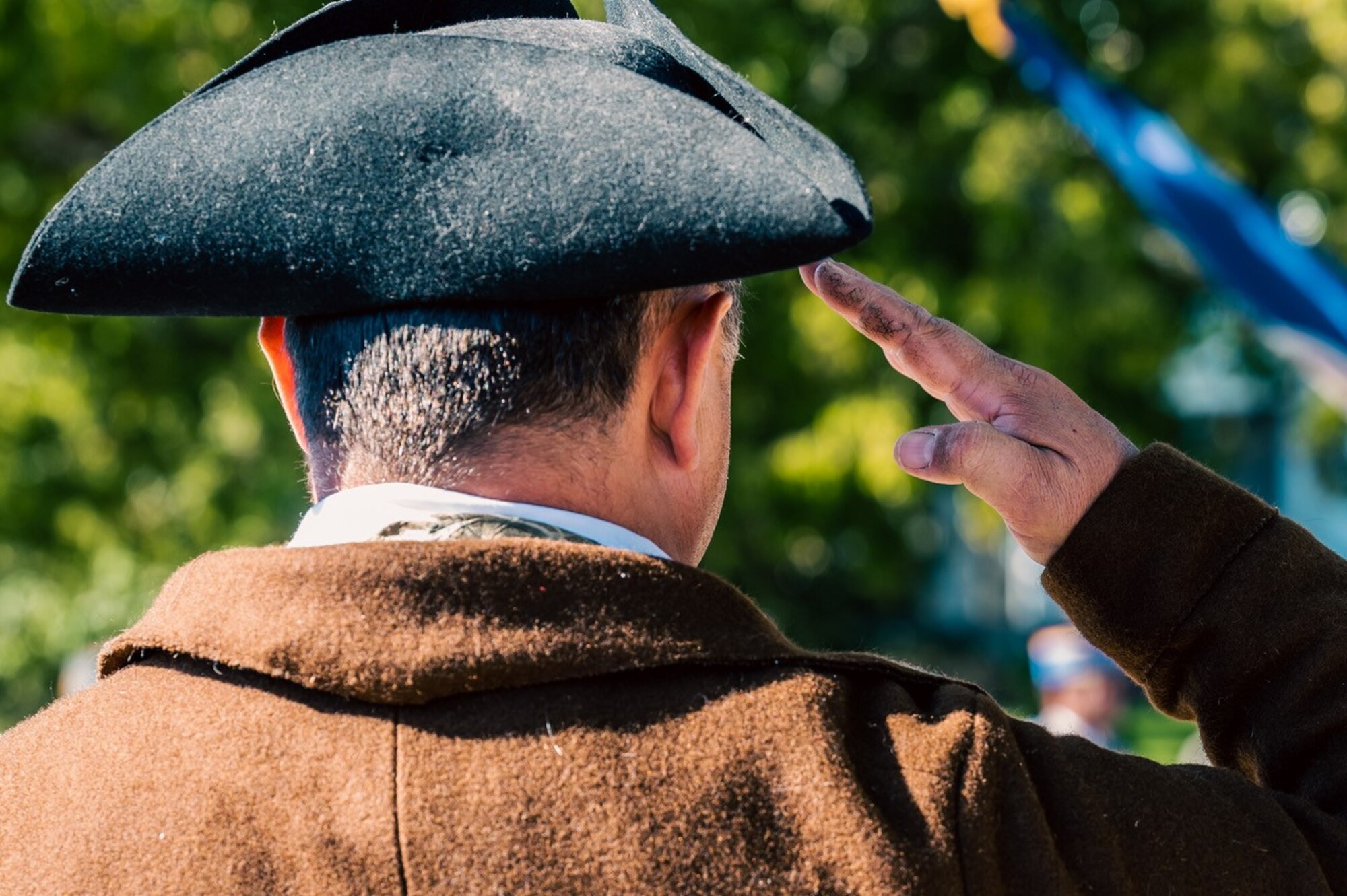 A spectator salutes the flags as they pass during the Yorktown Day Parade.