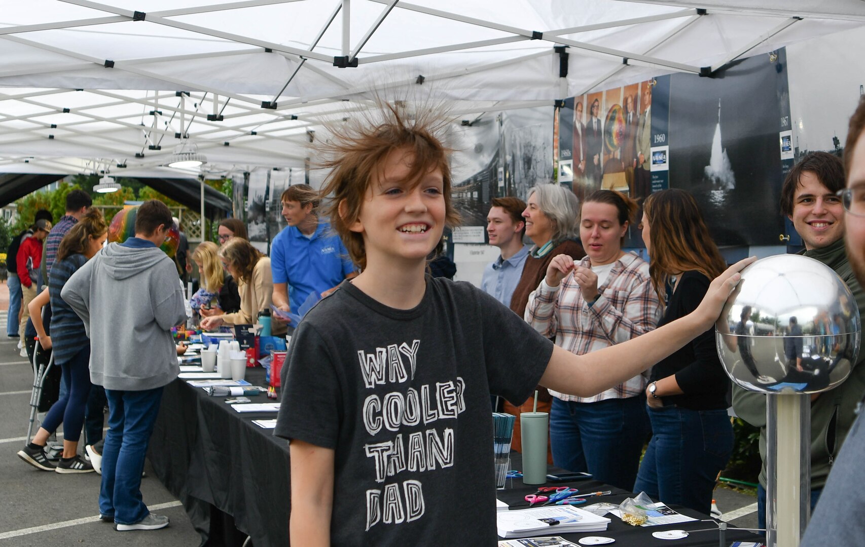 IMAGE: Tiernan Blunkosky, 11, touches the Van de Graaff generator that made his hair stand on end at the Naval Surface Warfare Center Dahlgren Division Dahlgren Downtown Forging Community Partnerships event Oct. 20 at The Silk Mill in Fredericksburg.