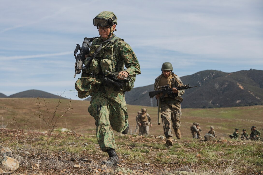 U.S. Marines with Combat Logistics Battalion 15, I Marine Expeditionary Force, and Singapore Guard pioneers with 7th Singapore Infantry Brigade, run to assemble explosives in an impact area during a combat engineer subject matter expert exchange as part of Exercise Valiant Mark 2023 at Camp Pendleton, CA, Oct. 13, 2023. Valiant Mark 23 is an annual, bilateral training exercise conducted between the Singapore Armed Forces and I Marine Expeditionary Force, designed to enhance interoperability, improve combined arms and amphibious warfighting skills, and strengthen military-to-military relationships. (U.S. Marine Corps photo by Staff Sgt. Dana Beesley)