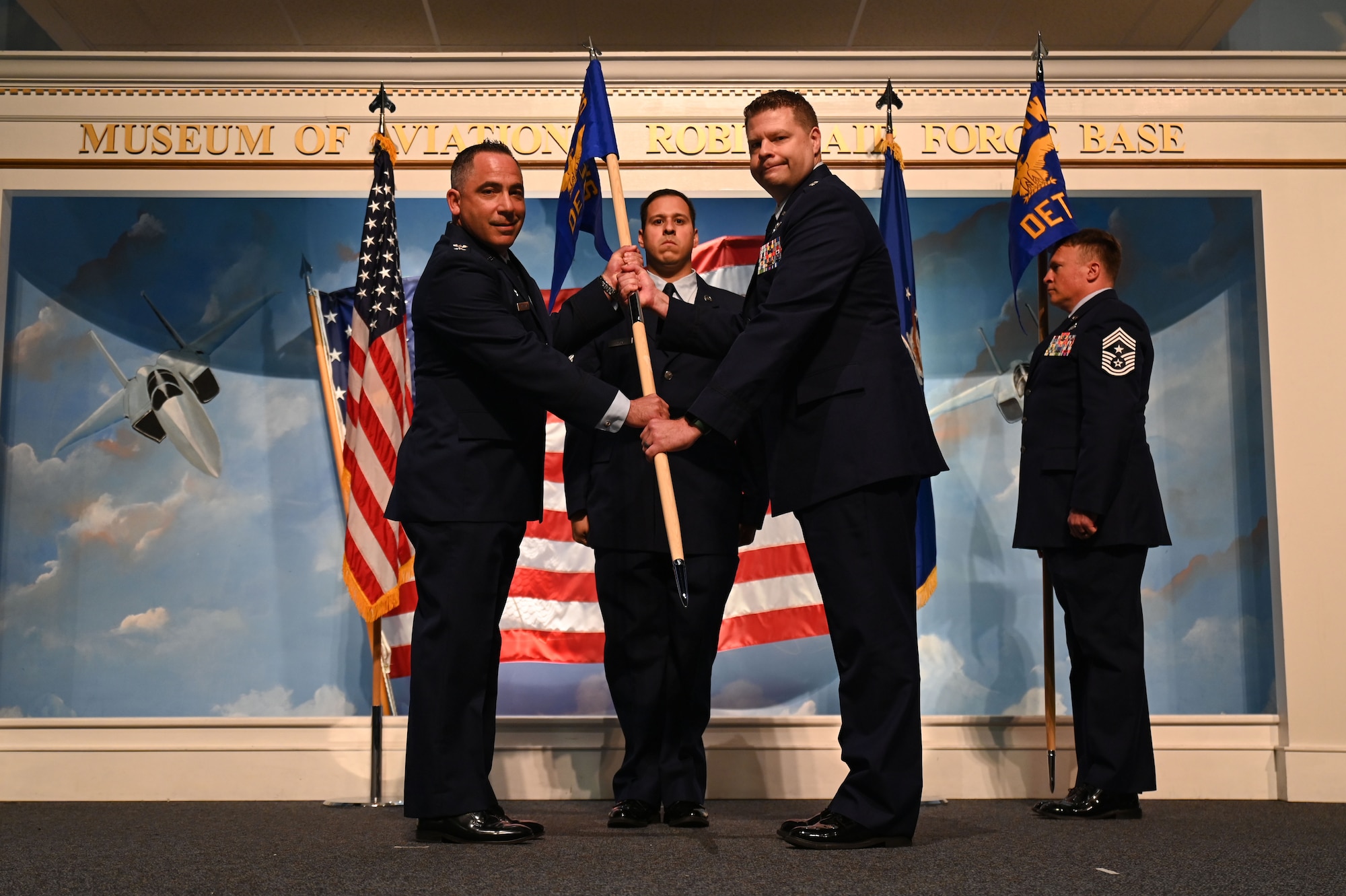 U.S. Air Force Col. Josh Koslov, 350th Spectrum Warfare Wing commander, left, passes the 350th SWW Det 1 guidon to U.S. Air Force Lt. Col. Christopher Ryan Cox, 350th SWW, Det 1 and 87th Electronic Warfare Squadron, Det 1 commander, right, at Robin Air Force Base, GA, Oct. 25, 2023. The activation of the 350th SWW, Det 1 is driven by the need for a dedicated focus on ensuring electronic warfare weapons systems will achieve combatant commanders’ intent when it matters most; in combat, as a unified fighting force. (U.S. Air Force photo by Staff Sgt. Ericka A. Woolever)