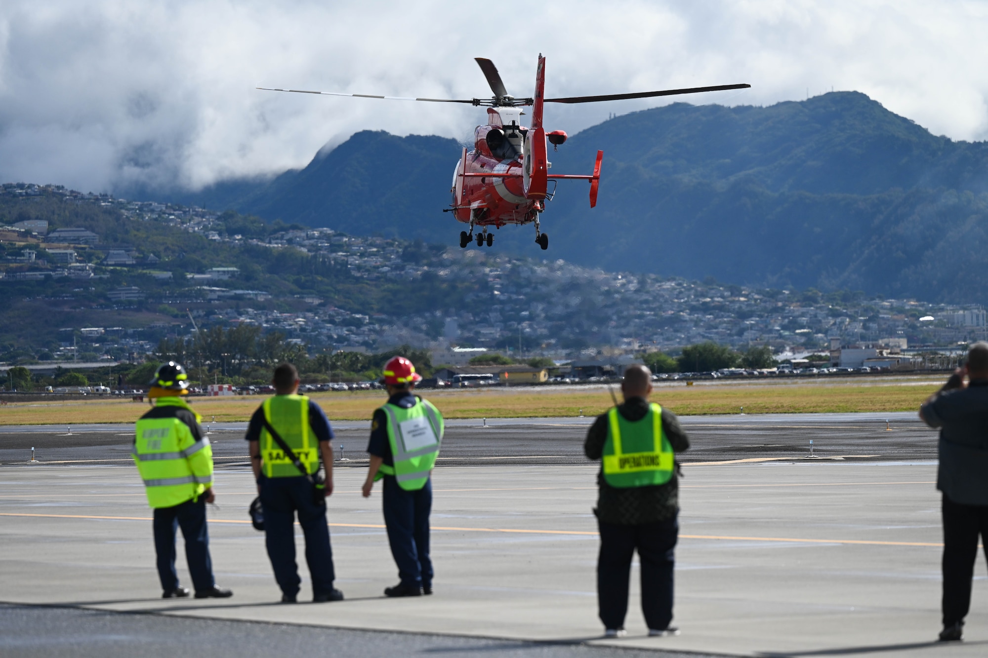 A Coast Guard MH-65 Dolphin helicopter departs carrying simulated patients during the triennial airport disaster exercise at Daniel K. Inouye International Airport, Oct. 20, 2023. Participating members included Hickam Airmen, City and County of Honolulu Fire Departments, Emergency Medical Services, American Medical Response, Federal Fire Department, U.S. Coast Guard, Federal Aviation Administration, State Department of Public Safety and nursing students from universities across the island. (U.S. Air Force photo by Senior Airman Makensie Cooper)