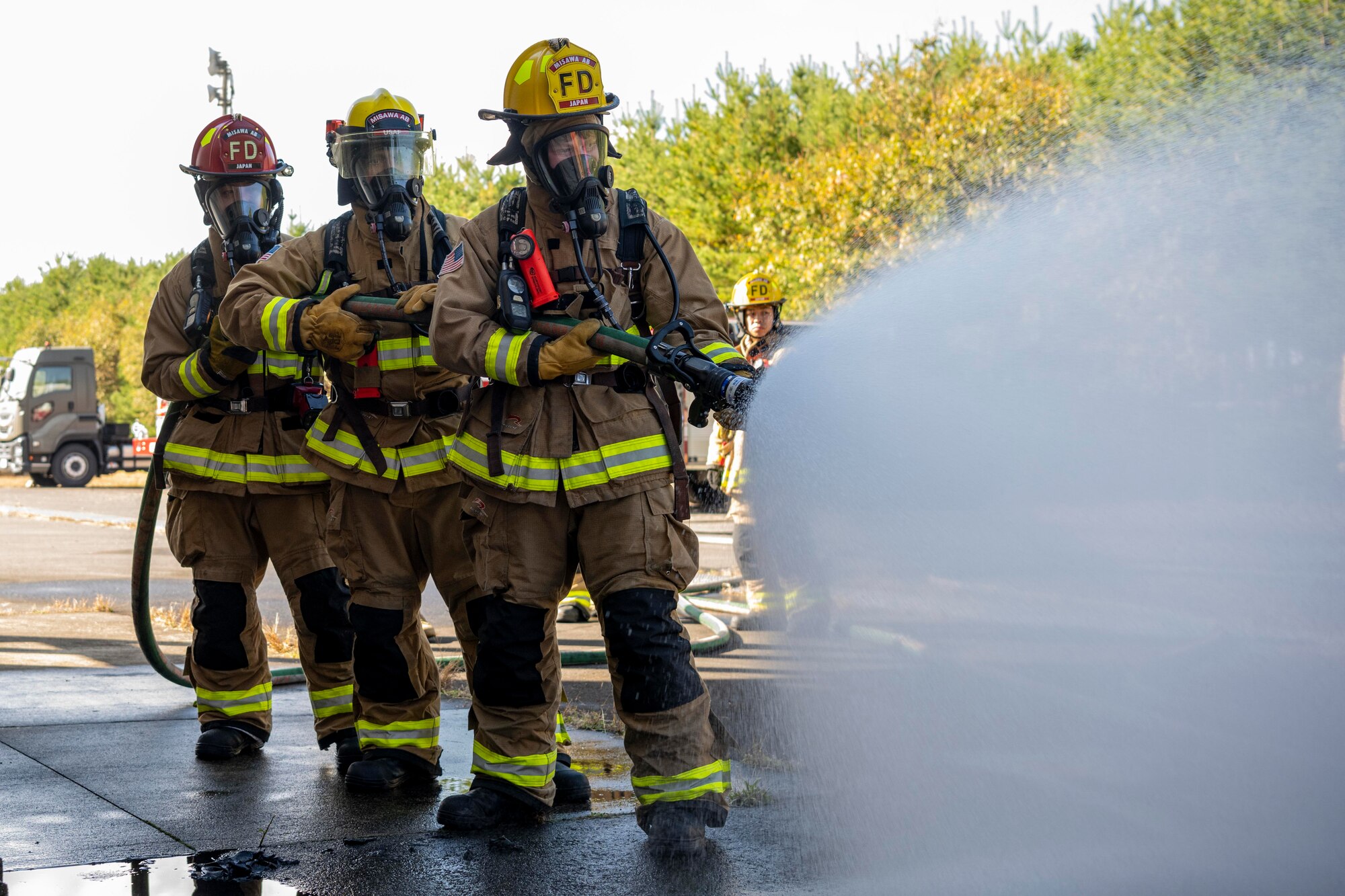 Firefighters spray a hose.