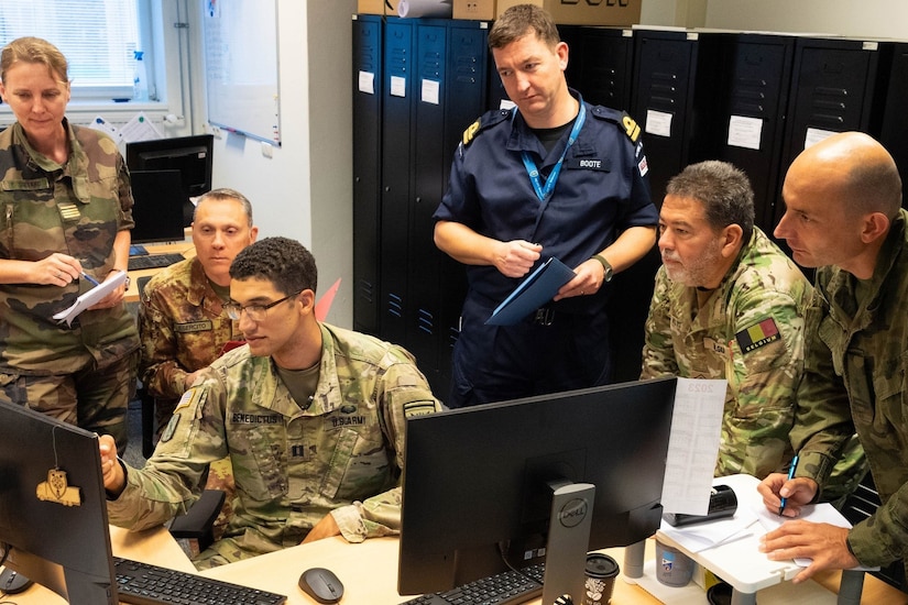 Service members stare at a computer.