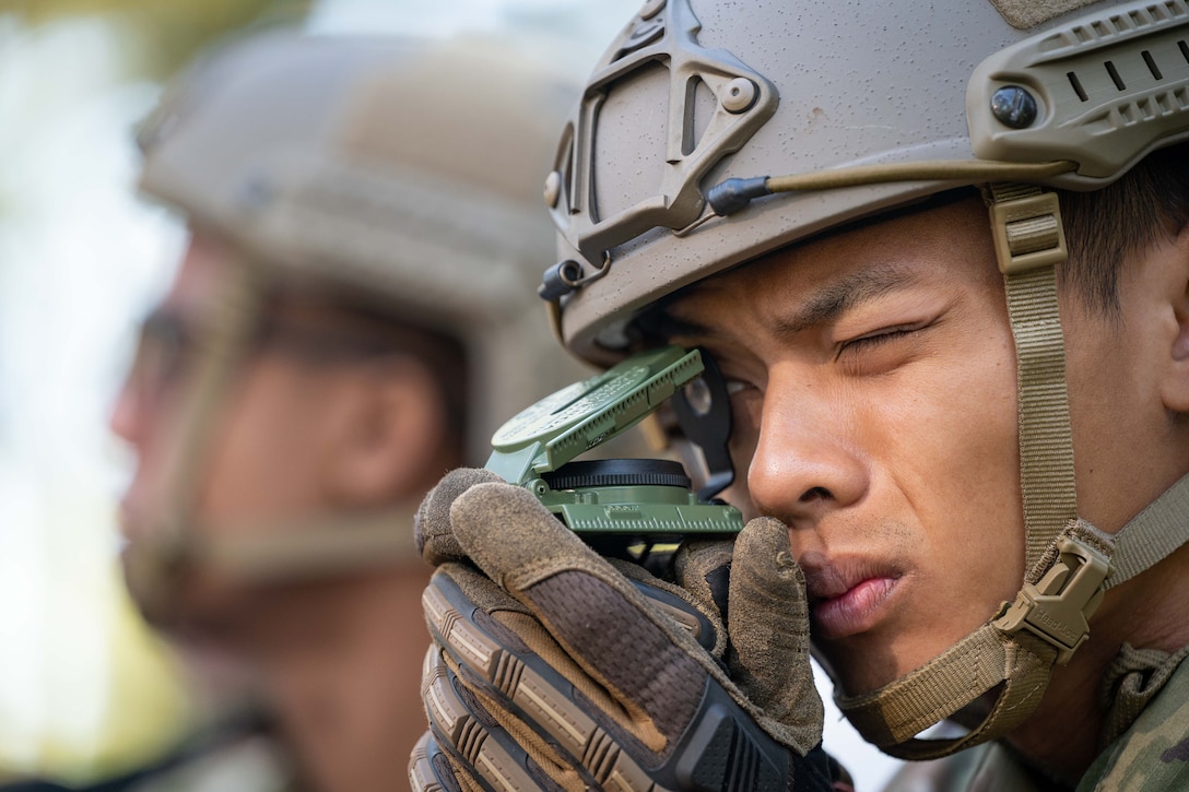 Close-up photo of an airman looking through a small compass.