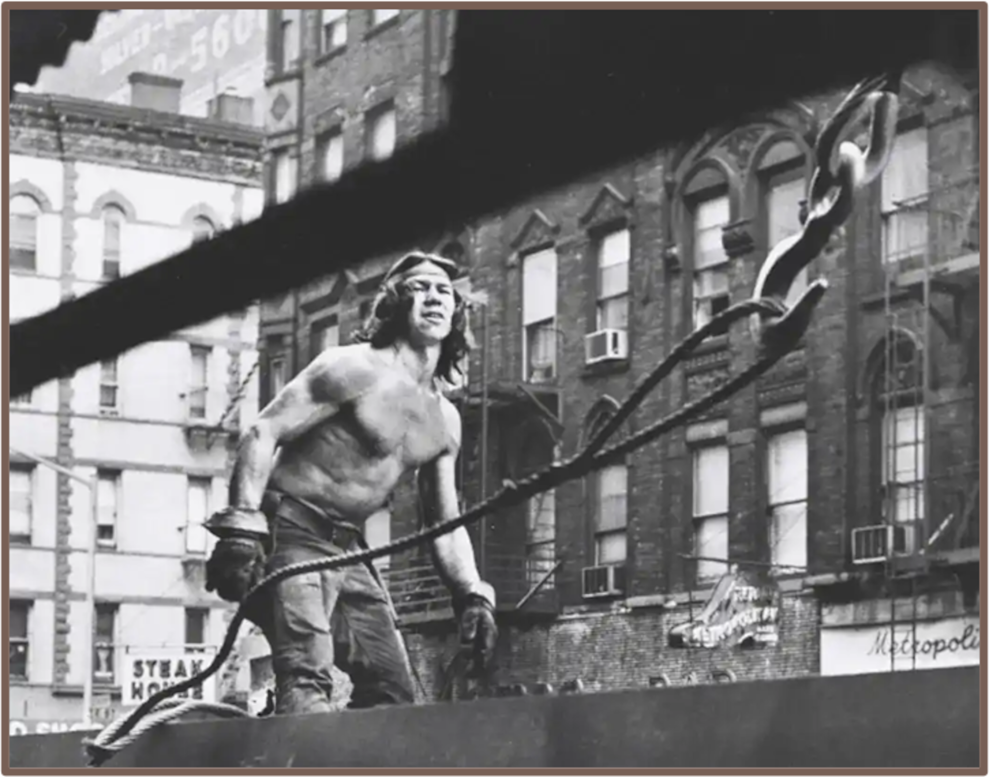 Black and white photo of a shirtless man working at a construction site.