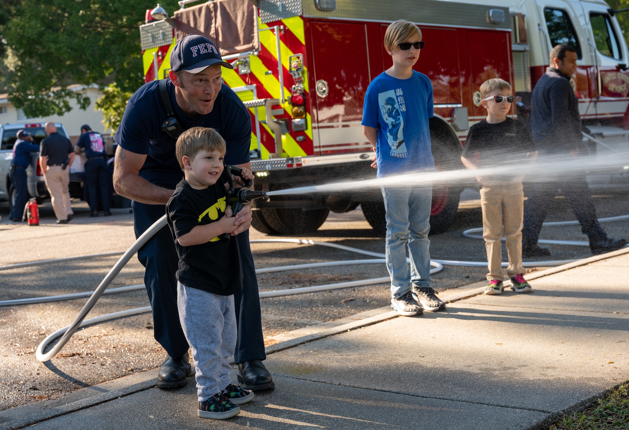 Fire fighter sprays fire hose with small child