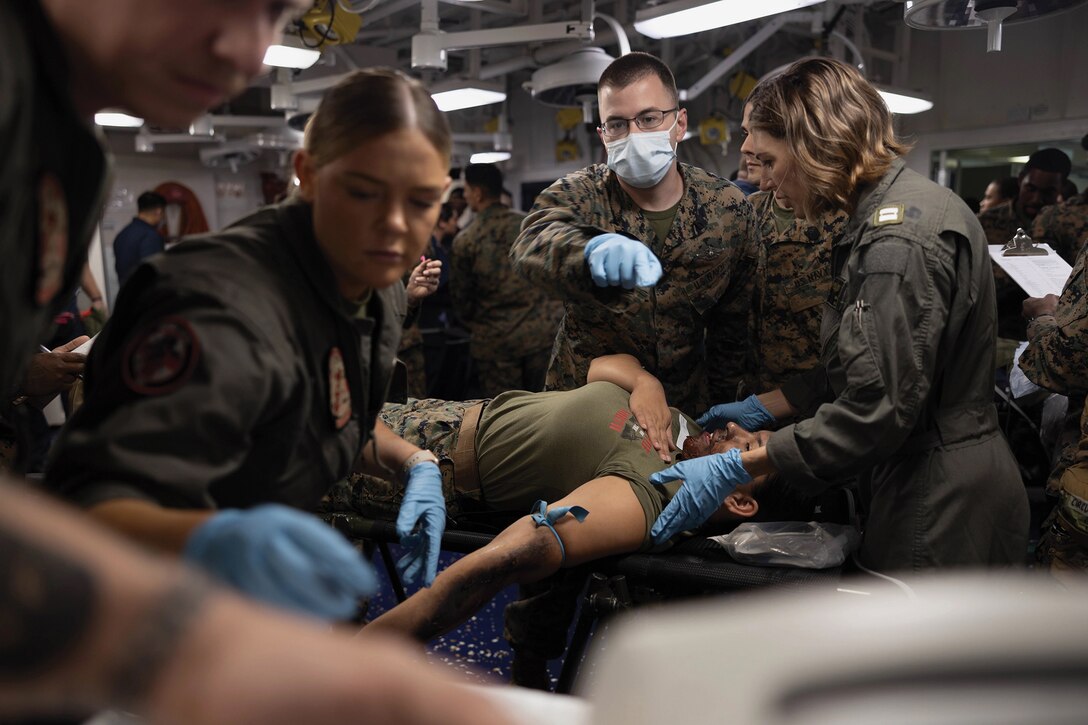 Navy Hospital Corpsman Second Class Jeffrey Ortberg, center, with Marine Medium Tiltrotor Squadron 265 (Reinforced), 31st Marine Expeditionary Unit, asks for assistance on simulated casualty during mass casualty exercise aboard amphibious assault ship USS America,