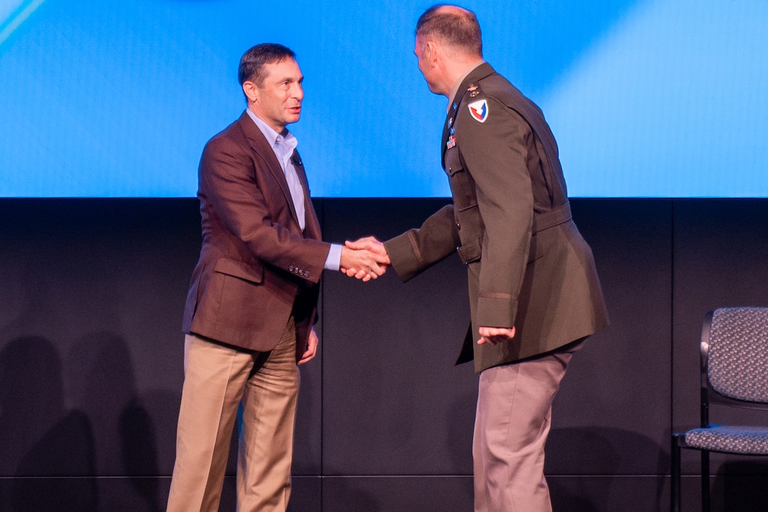 A person in a suit shakes hands with a person in a uniform.