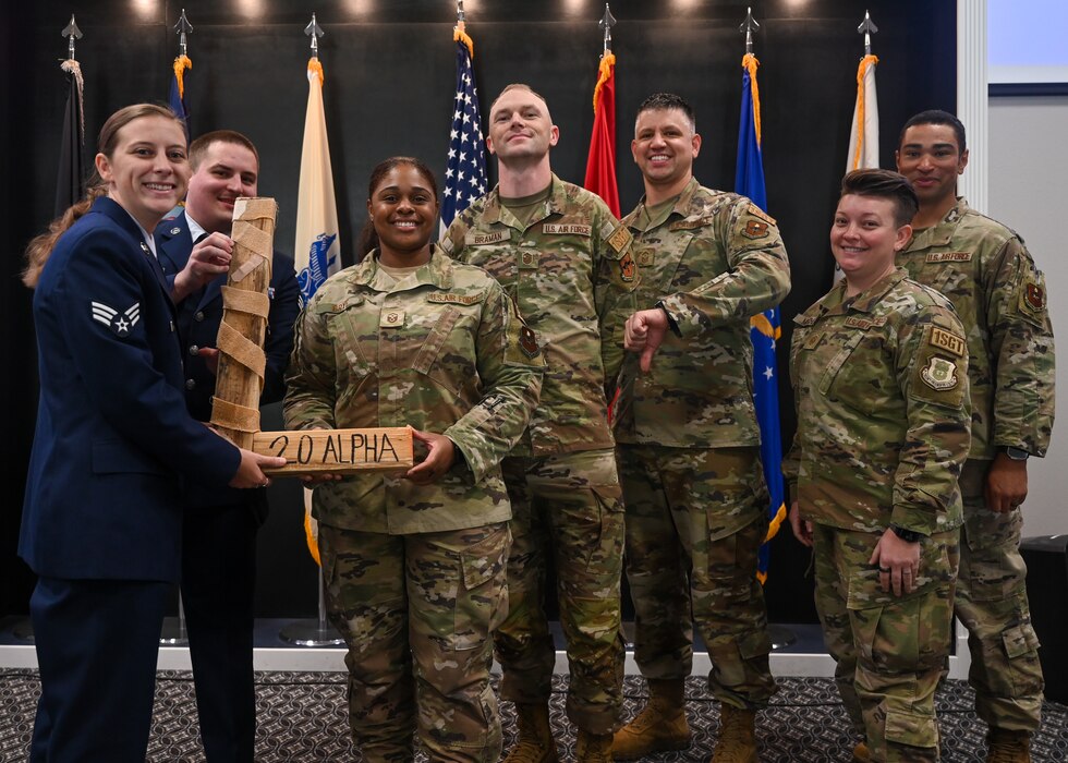 U.S. Air Force Senior Airmen Sydney Rodgers and Nicholas Larsen, Class 23-G Airman Leadership School graduates, present the “L” to a group of first sergeants belonging to the 17th Training Wing during the Class 23-G ALS graduation at the Powell Event Center, Goodfellow Air Force Base, Texas, Oct. 26, 2023. Every ALS class plays a volleyball game with the first sergeants, and the winning team presents the “L” to the losing team at graduation. (U.S. Air Force photo by Airman 1st Class Zach Heimbuch)