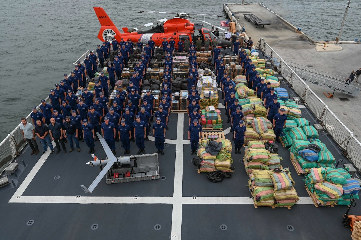 The crew of the Coast Guard Cutter James pose with more than $445 million in illegal drugs seized by Coast Guard and partner agencies in Port Everglades, Florida, Oct 26, 2023. The offload is a result of suspected drug smuggling interdictions in the Caribbean and Eastern Pacific Ocean. (U.S. Coast Guard photo by Petty Officer 3rd Class Eric Rodriguez.)