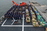 The crew of the Coast Guard Cutter James pose with more than $445 million in illegal drugs seized by Coast Guard and partner agencies in Port Everglades, Florida, Oct 26, 2023. The offload is a result of suspected drug smuggling interdictions in the Caribbean and Eastern Pacific Ocean. (U.S. Coast Guard photo by Petty Officer 3rd Class Eric Rodriguez.)