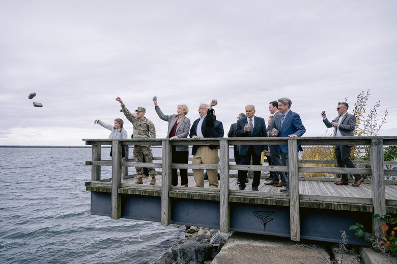 People toss stones from a wooden deck into the water of an abandoned shipping slip in Buffalo Harbor.