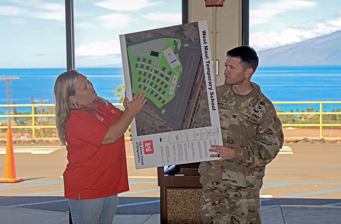Army officer holds graphic while USACE employees describes work being done.