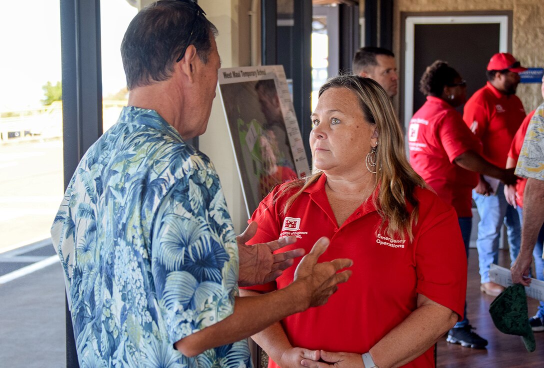 Corps of Engineers staff talks with member of public after a meeting.
