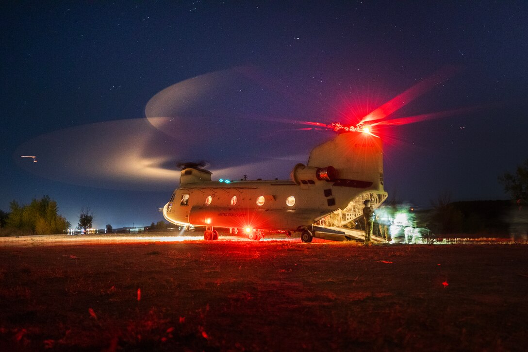 A helicopter rotor blades are seen as it lands at night.