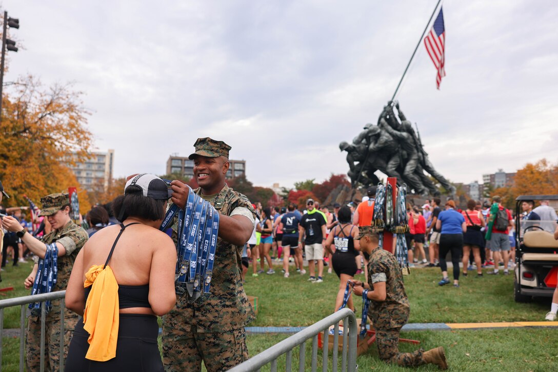 U.S. Marines award medals to runners for finishing the Marine Corps Marathon 10K in Arlington, Virginia, Oct. 29, 2023. Participants from around the world raced on the monumental MCM course through Washington, D.C., finishing at the Marine Corps War Memorial in Arlington, Virginia. The event was a celebration of every finisher’s honor, courage, and commitment to training for and completing the marathon. (U.S. Marine Corps photo by Lance Cpl. David Brandes)