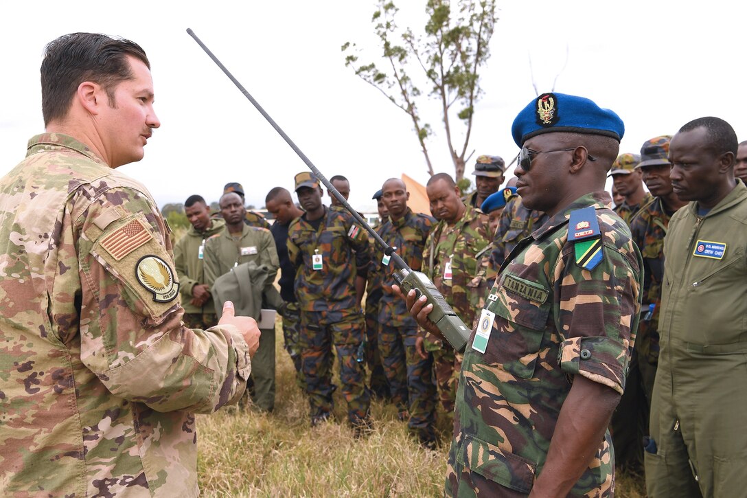 U.S. Air Force Technical Sergeant Jared Todd, 818th Mobility Support Advisory Squadron Survival, Evasion, Resistance and Escape air advisor, and Tanzania air force command Colonel Ian Haule discuss radio communication techniques at African Partnership Flight Kenya 2019, Laikipia Air Base, Kenya, August 22, 2019