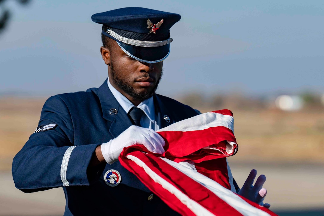 An airman folds an American flag.