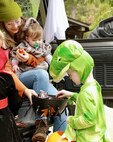 Dinosaur 3-year-old Dorian Stech picks out some candy at the trunk manned by 9-month-old Olivia Dosier and her mother, Casi Legler during the Illinois National Guard Family Programs "Trunk or Treat" on Oct. 28 on Camp Lincoln in Springfield, Illinois. The Illinois National Guard is also holding a Trunk or Treat for military families on Sunday, Oct. 29, 1-4 p.m., at the North Riverside Armory, 8660 W. Cermak Road, North Riverside, Illinois. The Trunk or Treat is a family and pet-friendly event open to servicemembers, veterans and their families throughout Chicagoland area. There will be costume contests with prizes for adults, children, and pets.