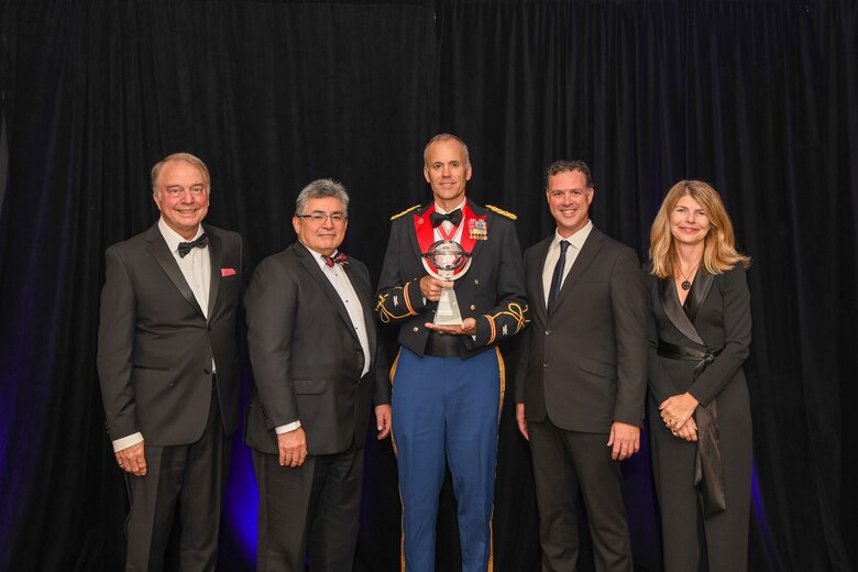 Group of people posing for a photo with an award