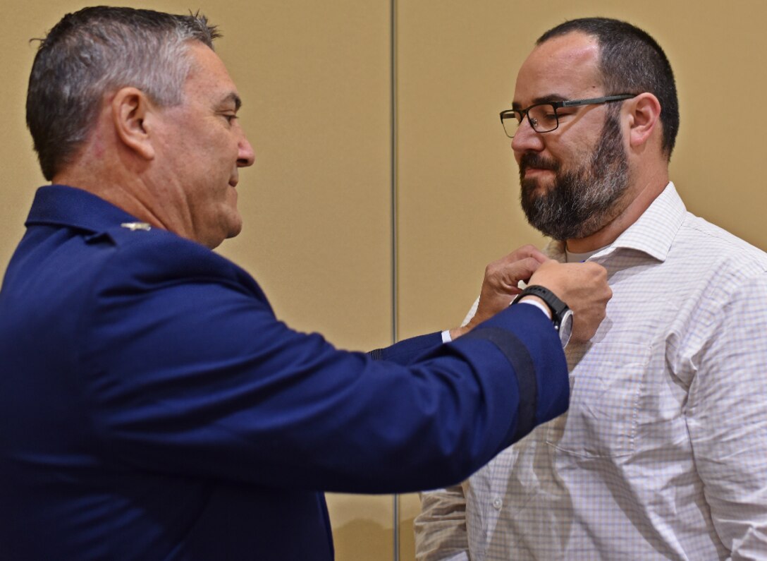 : Maj. Gen. Paul Knapp pins a Meritorious Service Medal to Cyber Response Team member Tim Greve.