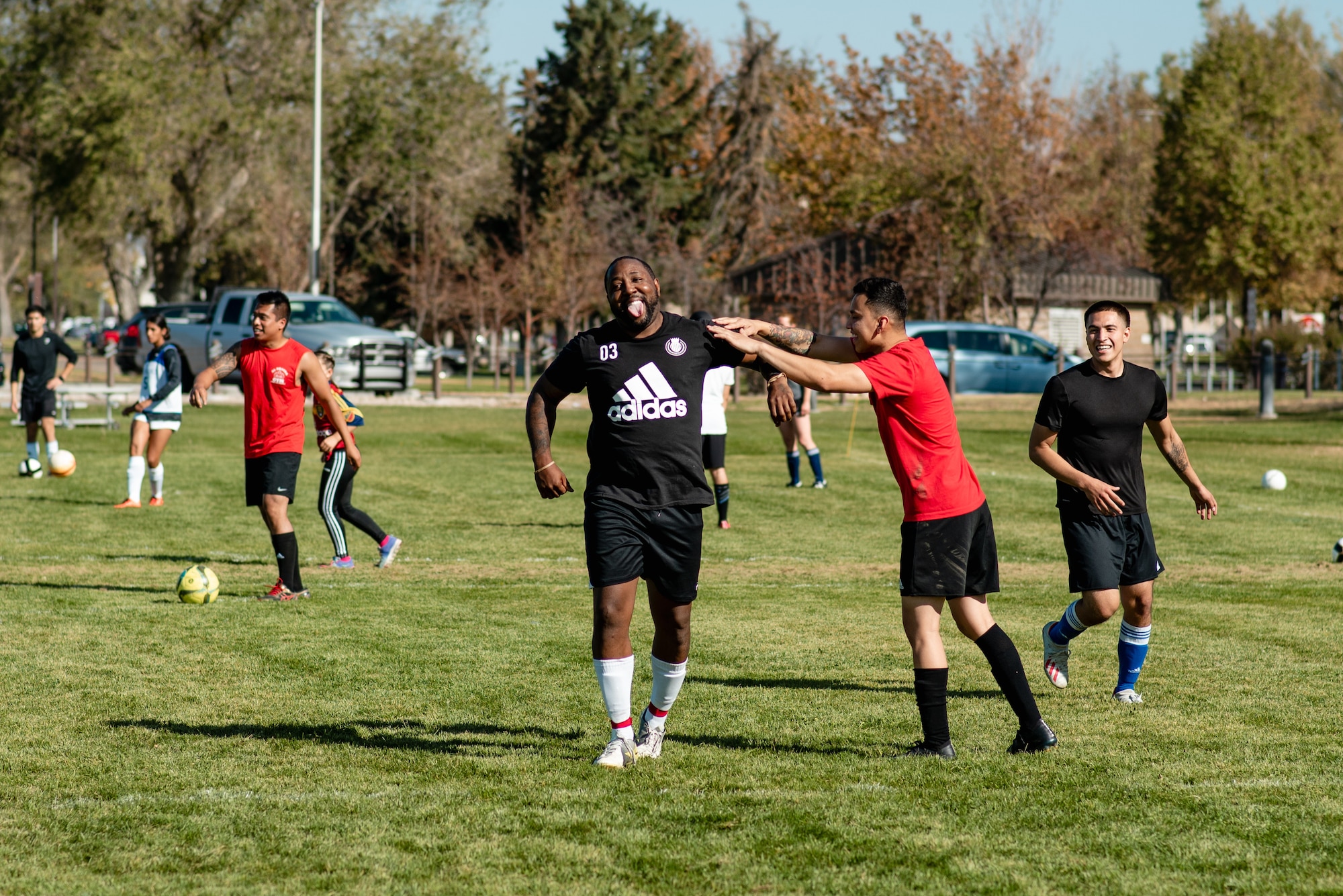 Several soccer players wearing black shirts and red shirts on the soccer field