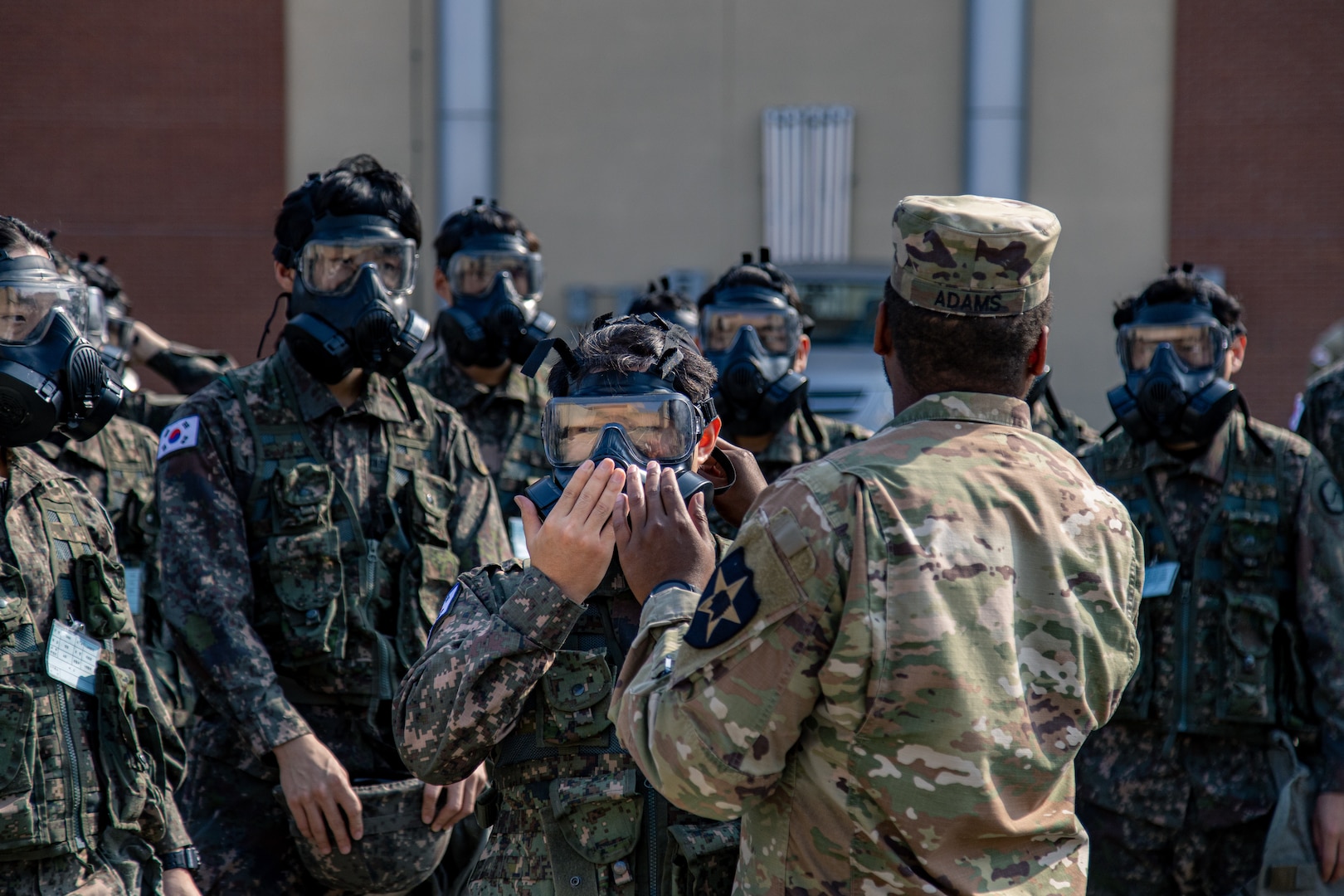 A U.S. Soldier from the 2nd Infantry Division, ROK-US Combined Division, instructs Korean Augmentation to the U.S. Army reserve soldiers on how to don their protective masks on U.S. Army Garrison Humphreys, South Korea, Oct. 25, 2023. (U.S. Army photo by Cpl. Choi, Kang Min)