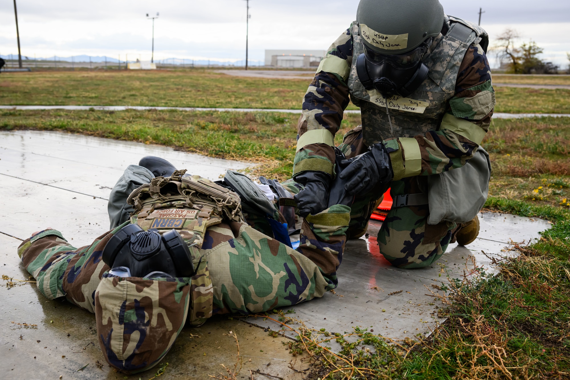 one Airmen tends to another while wearing chemical warfare suits.