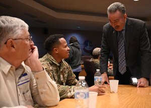 Cheyenne mayor leaning over a table, talking to an airman