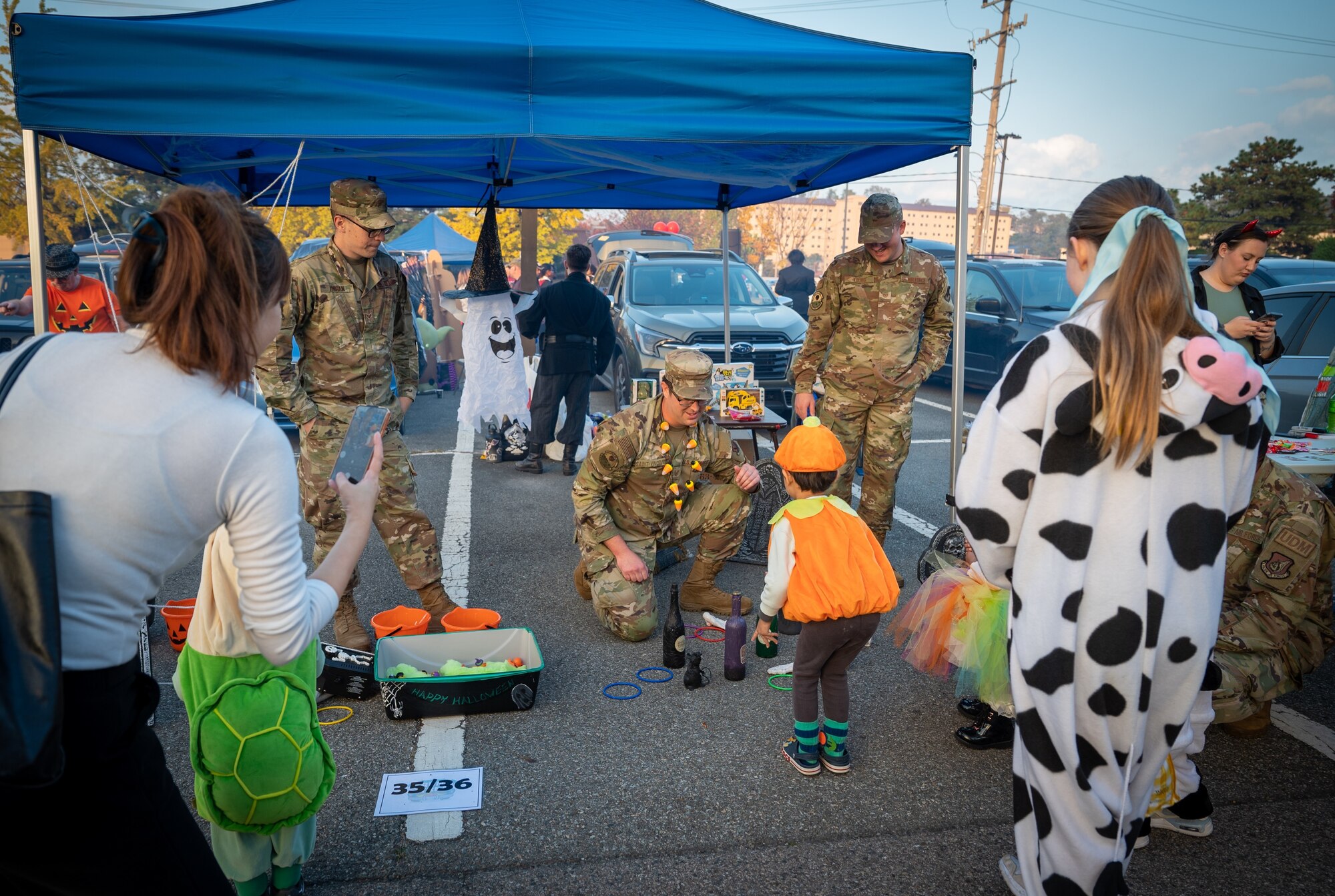 U.S. Air Force Tech. Sgt. Bryce Saint-Vincent, 6th Intelligence Squadron current intelligence cell section chief, helps a child play a ring-toss game during the Trunk-or-Treat event at Osan Air Base, Republic of Korea, Oct. 27, 2023. The event had games, food and entertainment for military members and their families to celebrate Halloween and foster community morale. (U.S. Air Force photo by Staff Sgt. Kelsea Caballero)