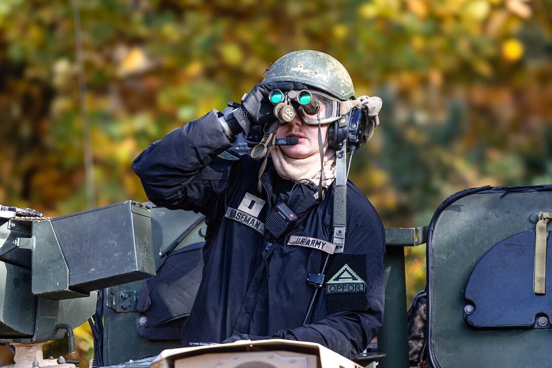 A soldier looks through binoculars.