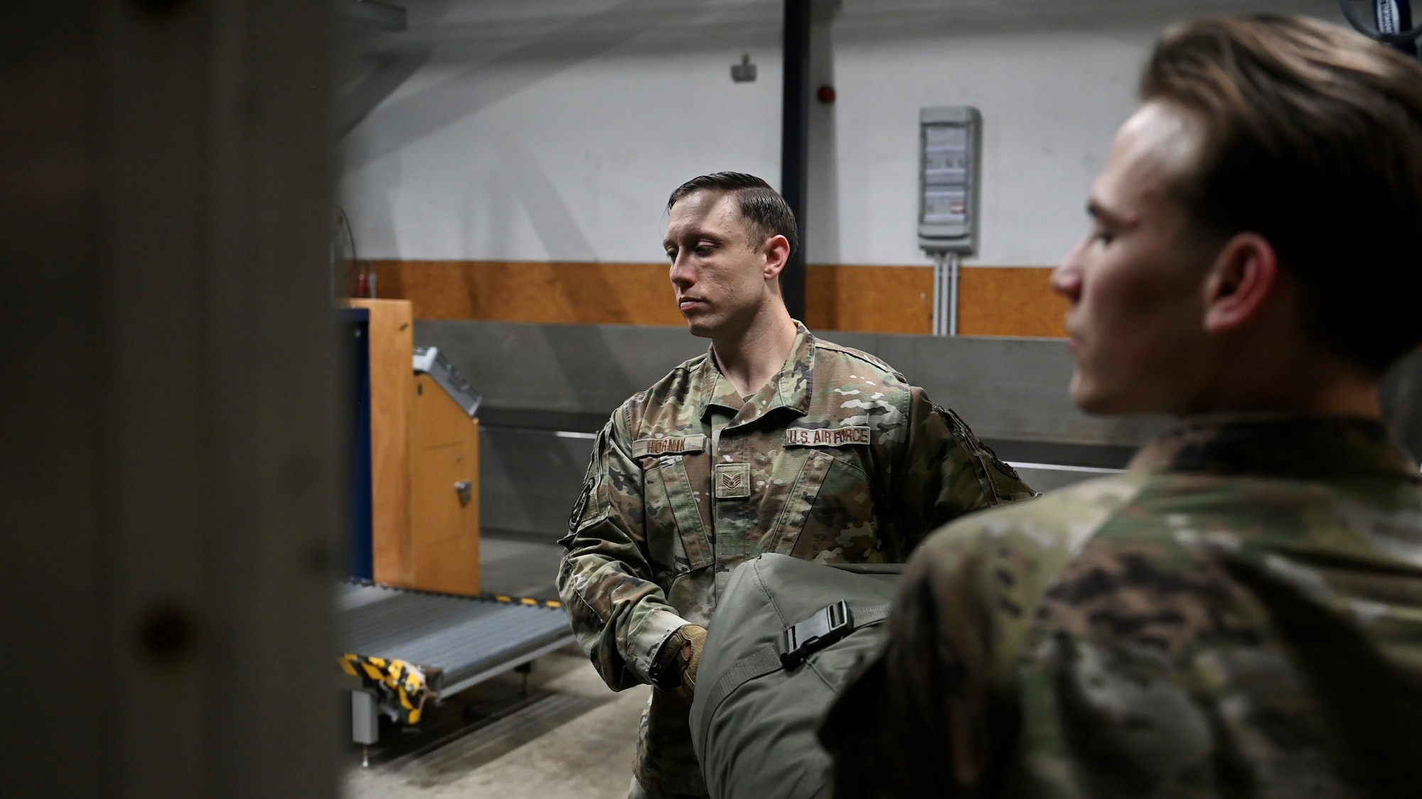 Staff Sgt. Stephen Hornik, a passenger services supervisor assigned to the 721st Aerial Port Squadron, and another 721st APS Airman move a piece of luggage to be loaded onto a plane at the passenger terminal on Ramstein Air Base, Germany, Oct. 25, 2023.